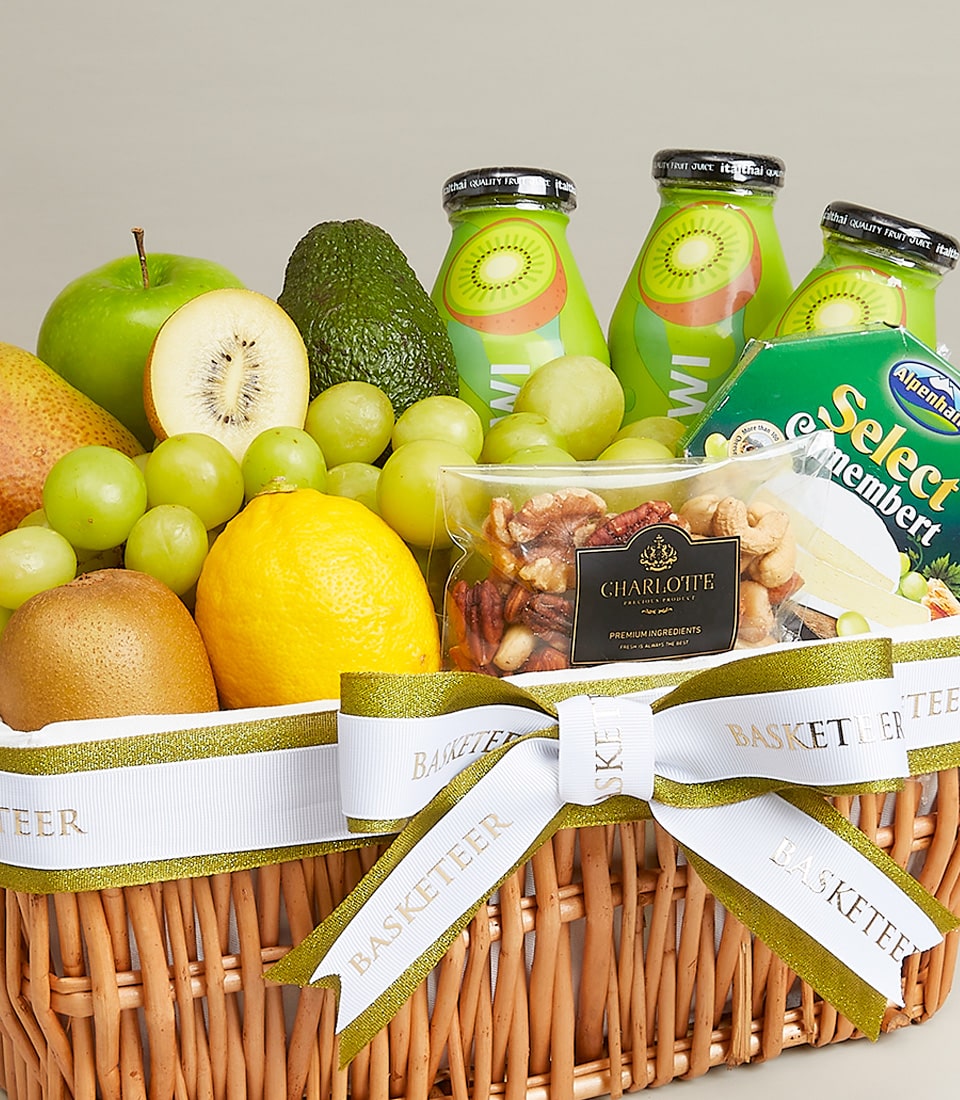 Woven wicker gift basket with fresh apples, kiwis, grapes, cheese, and gourmet nuts, tied with white and gold ribbon