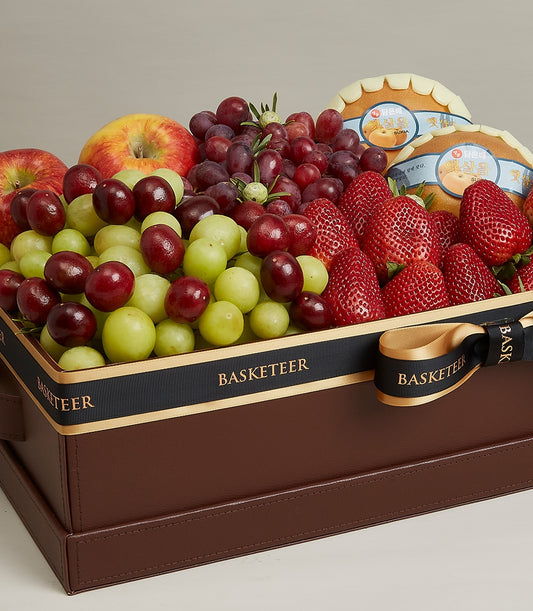 Luxury fruit gift box with fresh grapes, apples, strawberries, and pears in dark brown leather-like packaging with black and