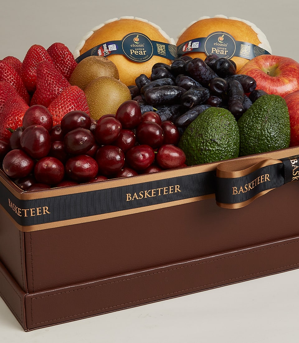Basketeer luxury gift basket Bangkok, featuring strawberries, Asian pears, cherries, and avocados in a leather-style box with a black ribbon.