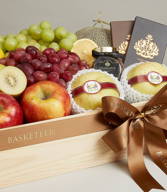 Luxurious wooden crate gift basket filled with fresh grapes, apples, pears, and gourmet products with brown satin ribbon