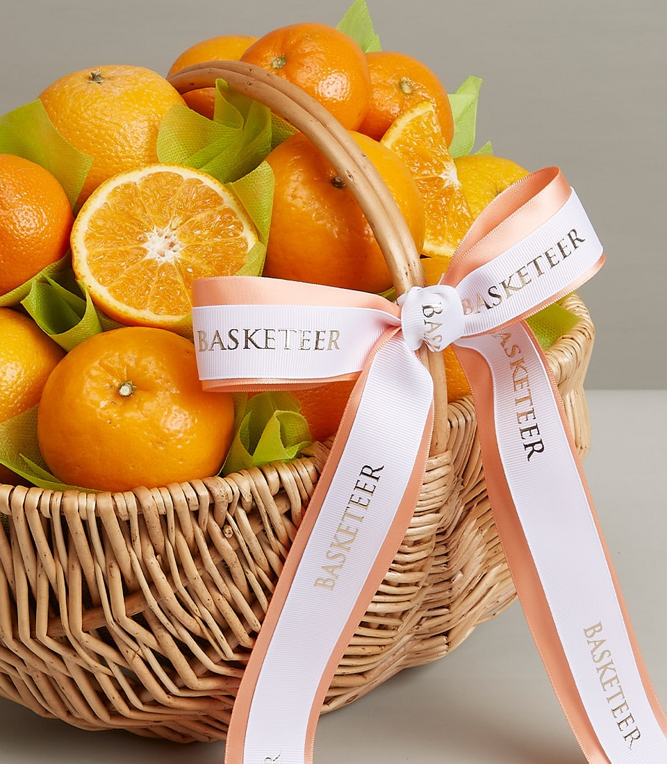 Premium orange gift basket with fresh citrus and tissue wrapping, tied with peach ribbon
