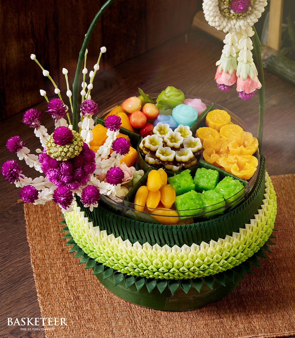 Tiered green banana leaf gift basket with colorful Thai desserts and purple flowers, Songkran celebration hamper