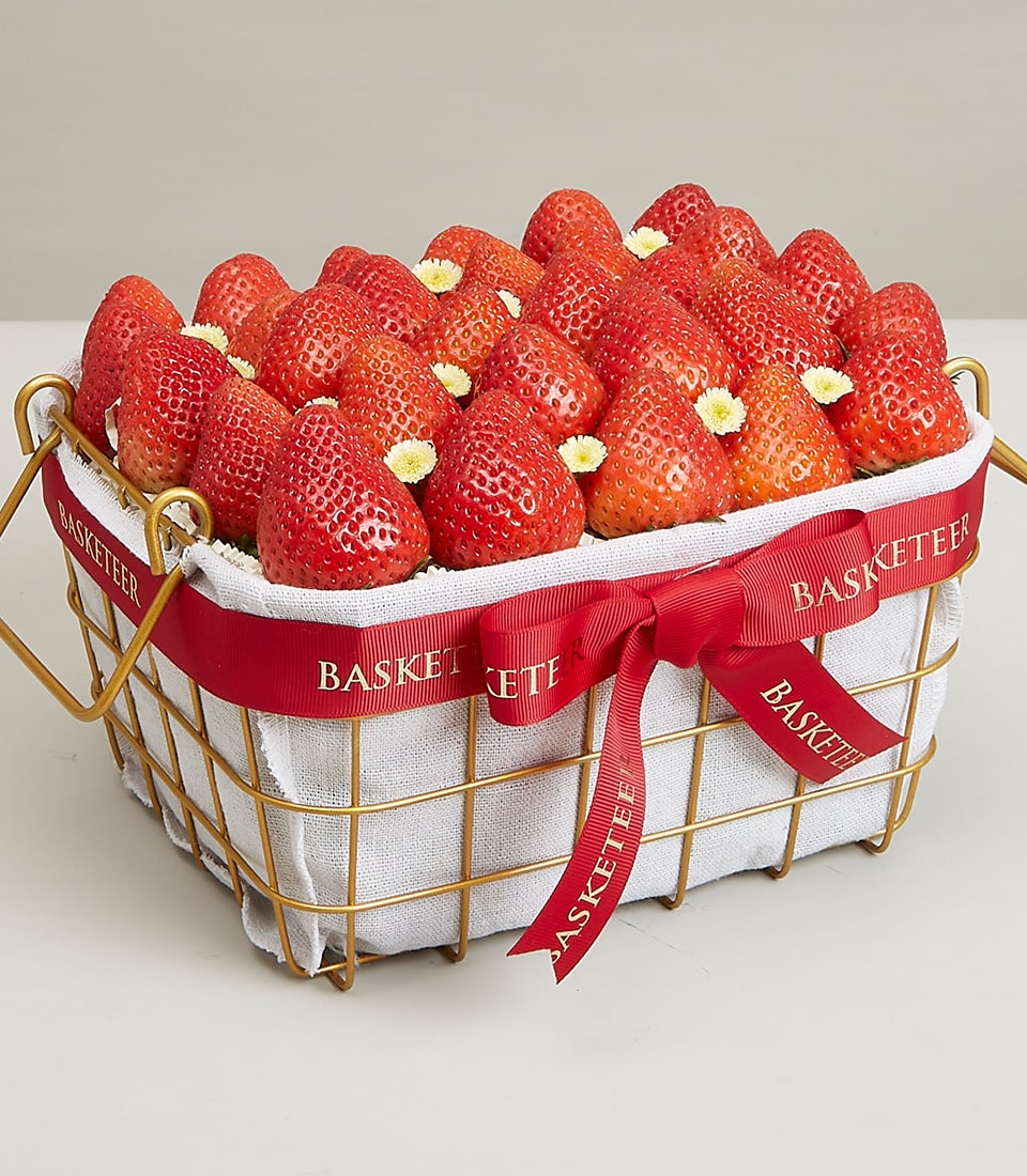 Luxury gold wire basket of fresh ripe strawberries with white flowers and red ribbon bow