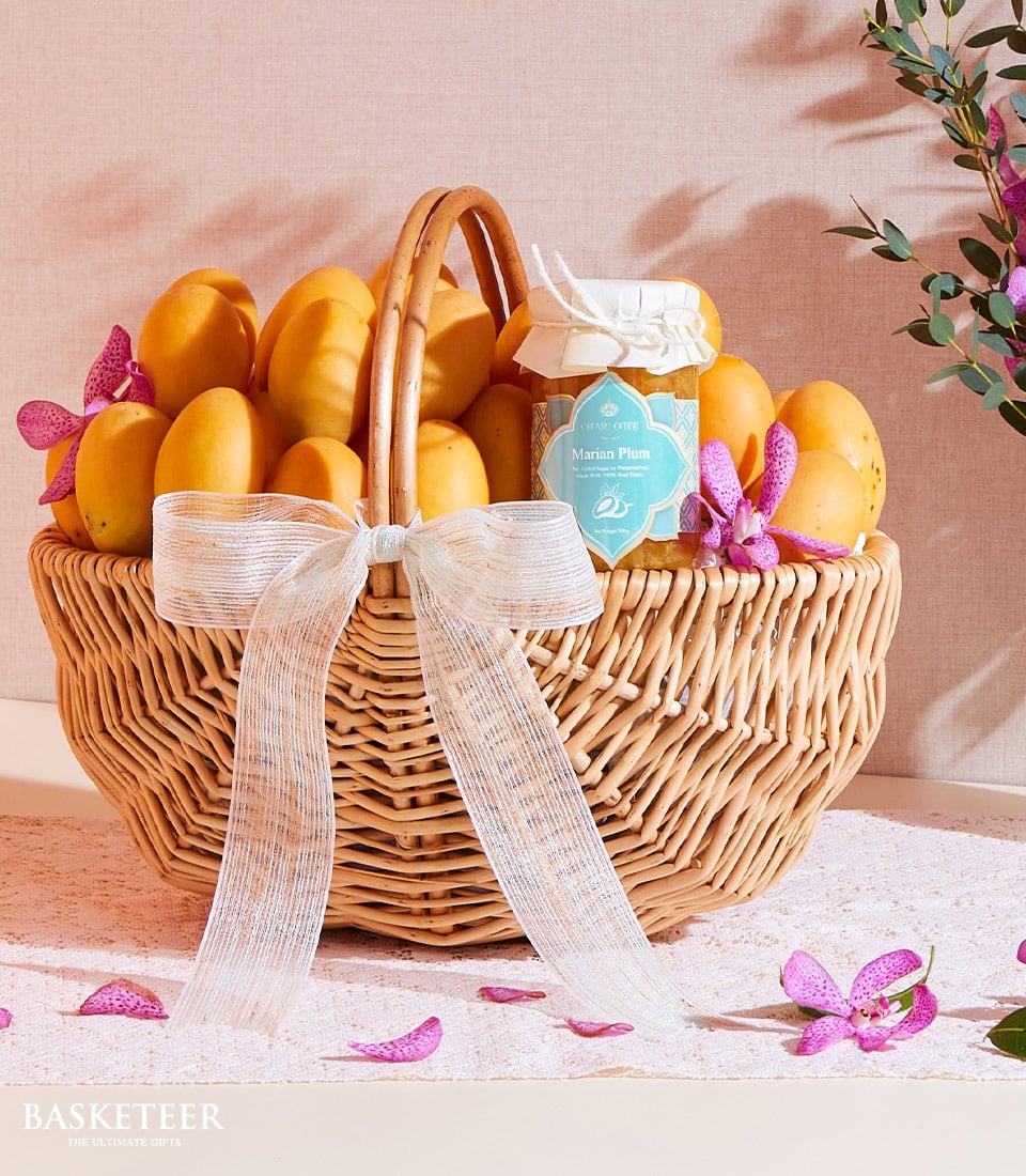 Golden mango gift basket with Marian plum jam and orchid accents, tied with white ribbon