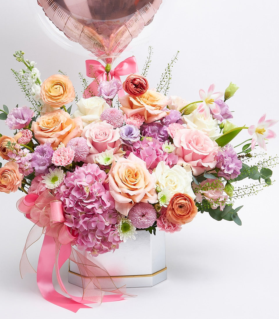 Vibrant pink and peach roses with heart balloon in white hexagonal luxury gift box