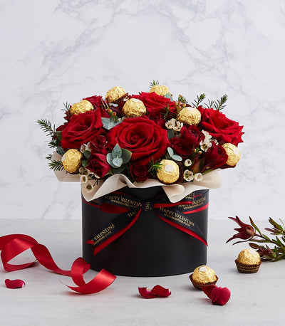 Luxe red roses and Ferrero chocolates in black cylindrical gift box with eucalyptus, perfect for birthdays and anniversaries