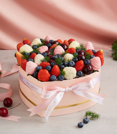 Heart-shaped pink gift box with chocolate-dipped strawberries, berries, and fresh fruit for Valentine's Day