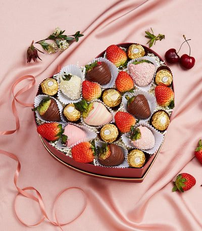 Heart-shaped luxury gift box with chocolate-covered strawberries, Ferrero Rocher, and fresh cherries on pink satin