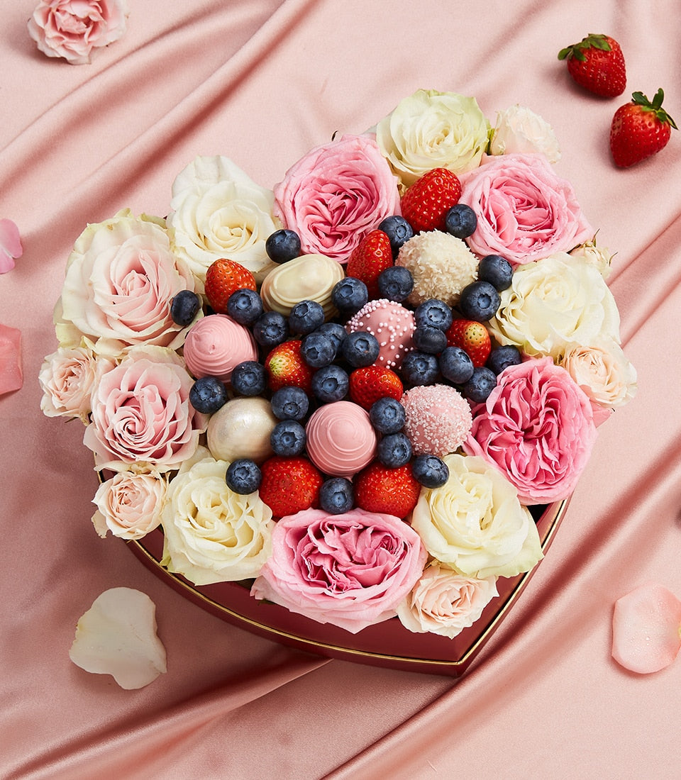 Heart-shaped luxury gift box with fresh berries, chocolate truffles, and pink roses on satin