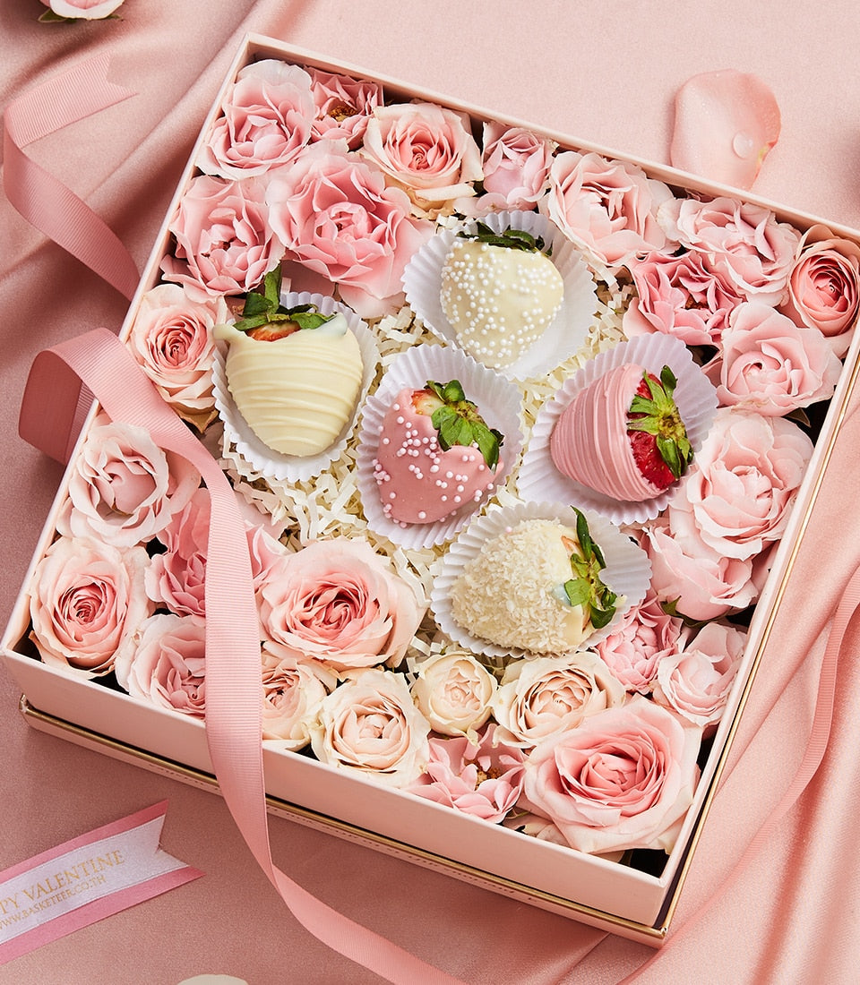 Blush pink Valentine gift box with chocolate-covered strawberries, roses, and white ribbon