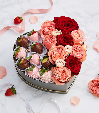 Heart-shaped luxury gift box with chocolate-dipped strawberries and fresh roses in red, coral, and pink