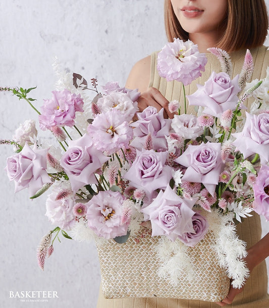 Light purple roses and eustoma get well flower gift basket with white filler blooms in woven straw holder