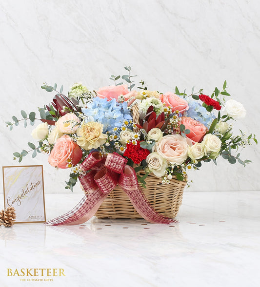 Vibrant fresh flower basket with hydrangeas, roses, carnations, and daisies in woven basket with red ribbon