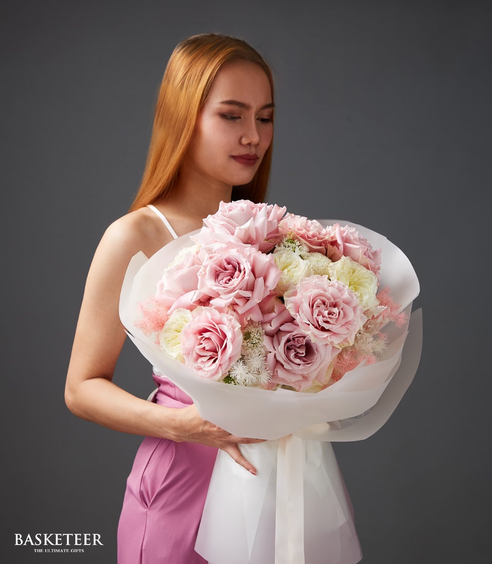 Ethereal blush pink roses and white flowers bouquet with feathery accents, gift-wrapped in white paper