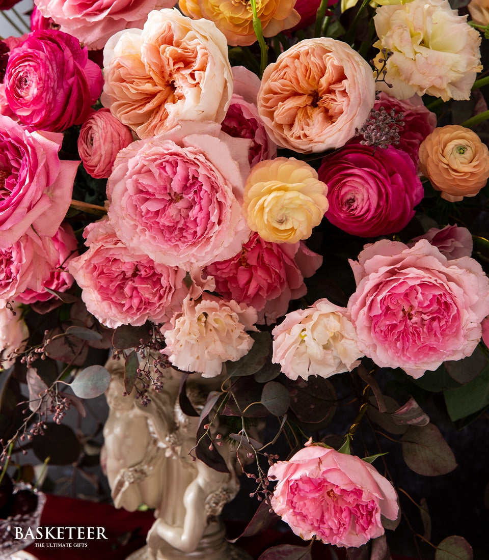 Luxury rose and ranunculus arrangement in pink, peach, and cream tones with English-style decorative vase
