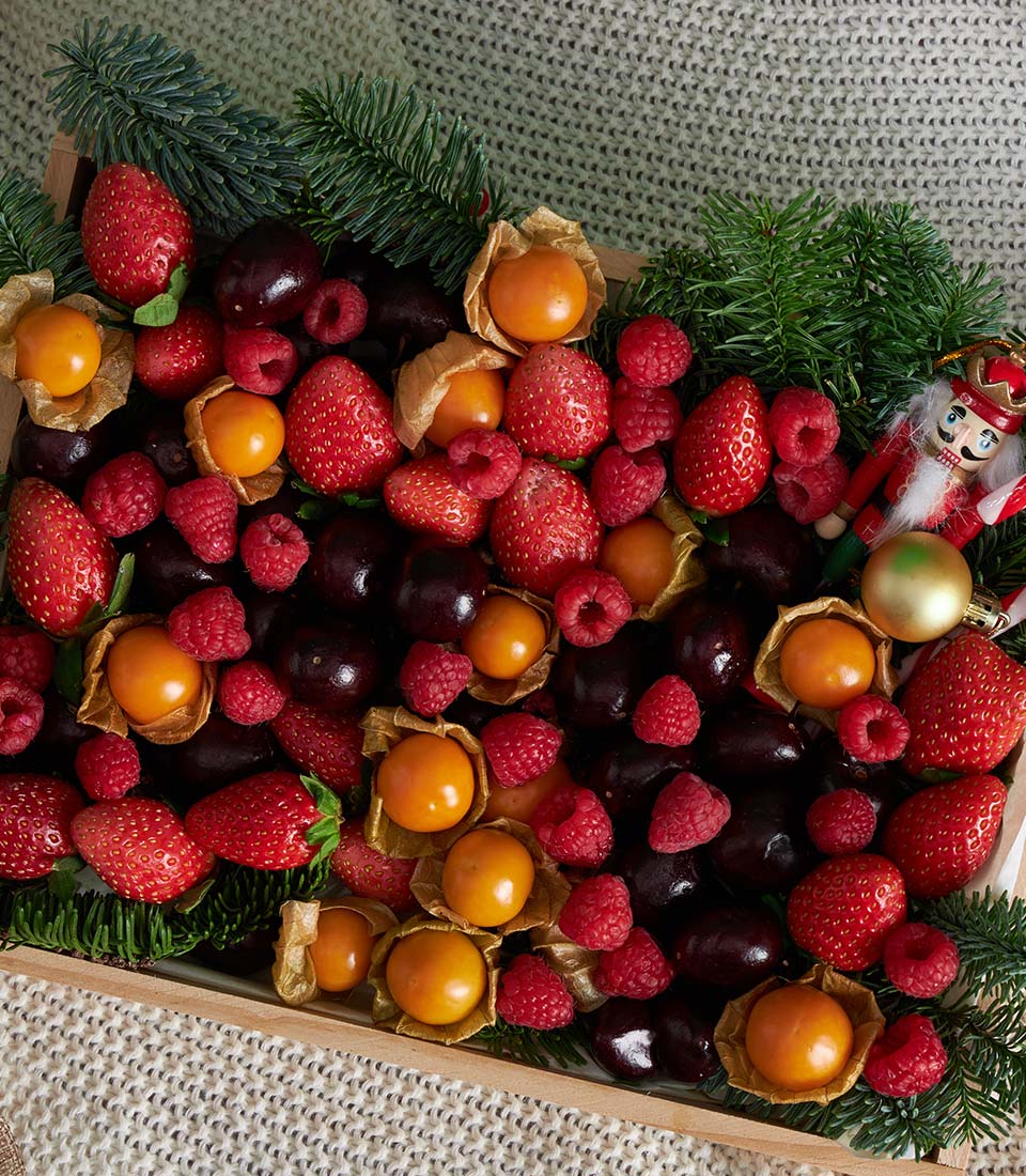 Festive Berry Fruit Gift Box with strawberries, raspberries, physalis, and cherries in wooden tray with holiday greenery