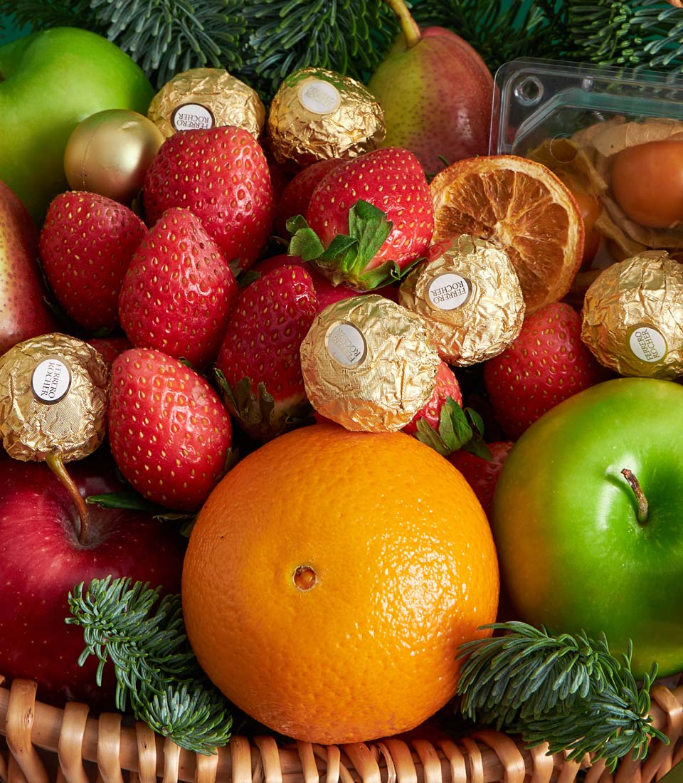 Festive wicker basket with fresh fruit, Ferrero chocolates, and holiday greenery