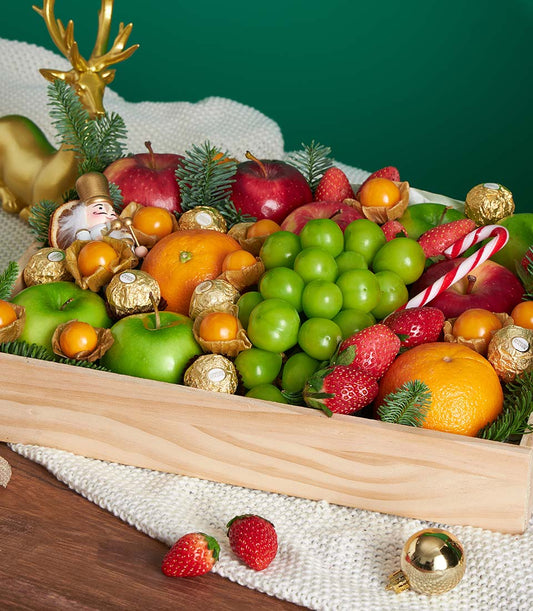 Luxury festive mixed fruit gift box with apples, grapes, strawberries and chocolates in wooden crate