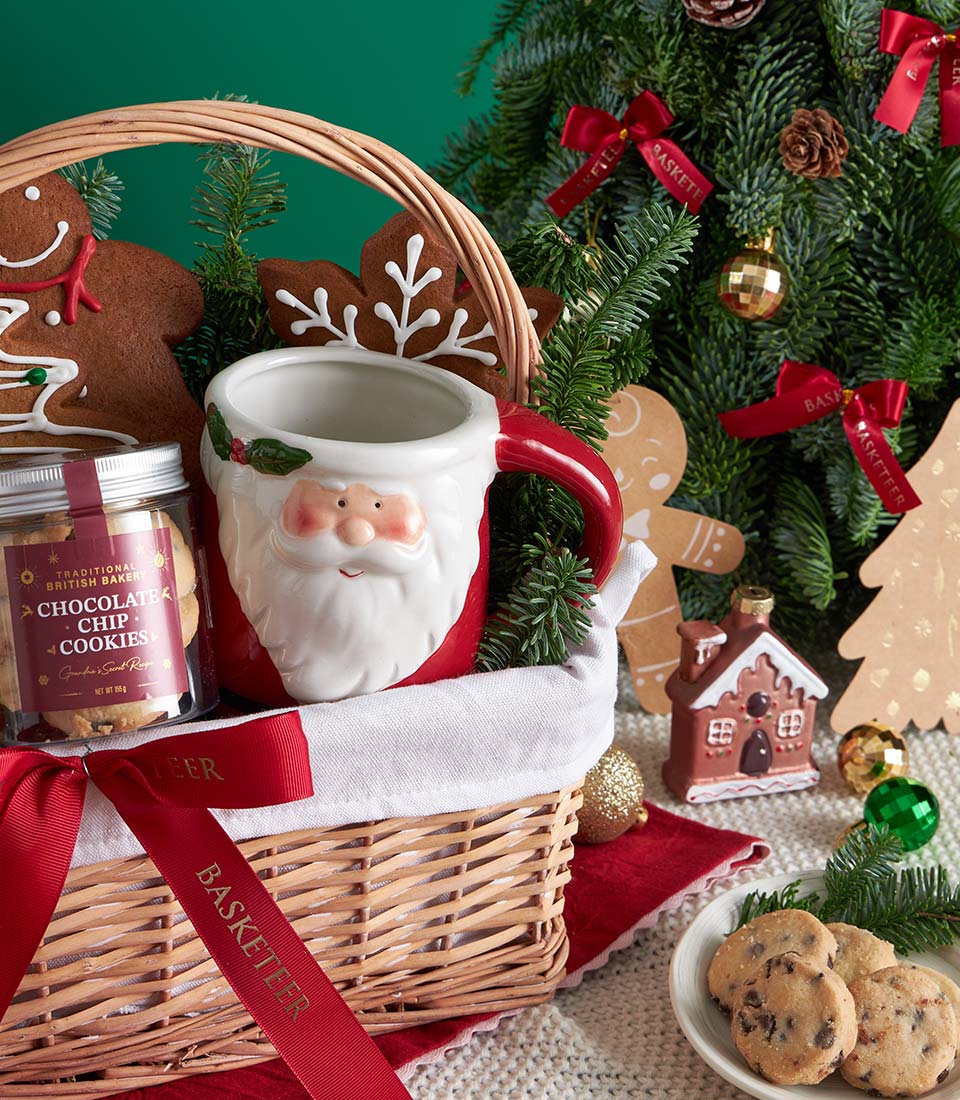 Festive Christmas gift basket with Santa mug, gingerbread cookies, and chocolate chip treats in wicker