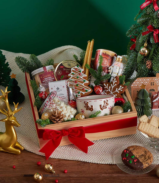 Festive Christmas gift box with shortbread cookies, chocolate treats, and holiday decorations tied in red velvet