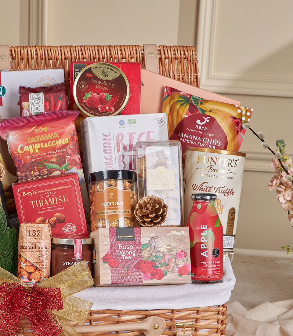 Wicker hamper filled with gourmet coffee, tea, chocolates, and snacks tied with festive red and gold ribbon, ideal New Year