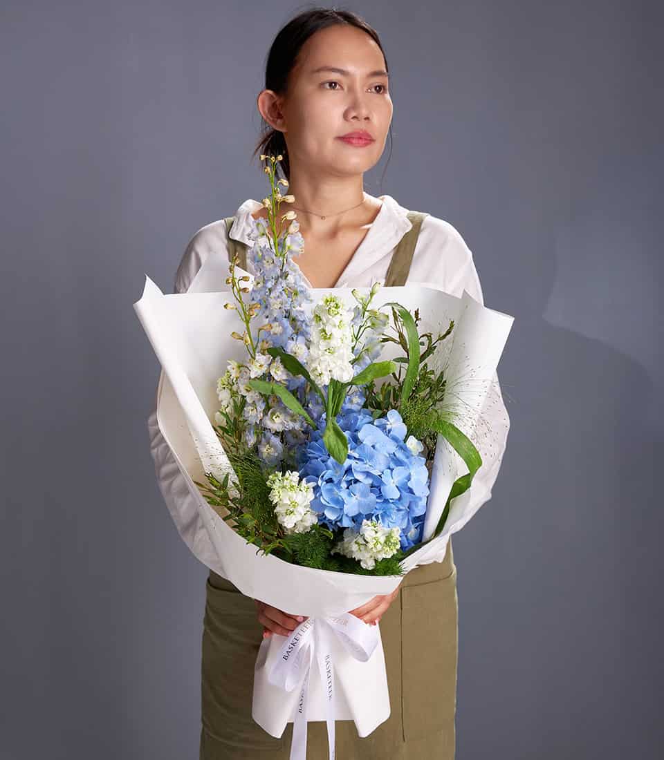 Blue hydrangea and white stock elegant bouquet with delphinium and greenery, wrapped in white paper