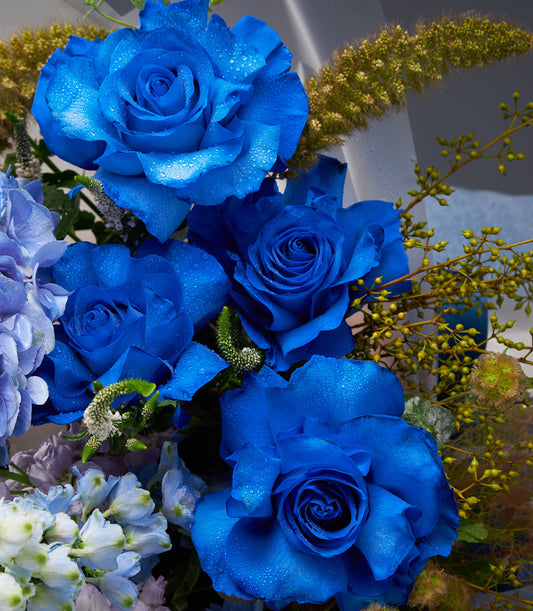 Deep blue roses with delphiniums, hydrangea, and berries in fresh luxury bouquet