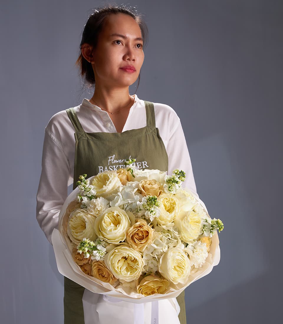 Ivory garden rose and white hydrangea bouquet with cream and pale orange roses, wrapped in white paper
