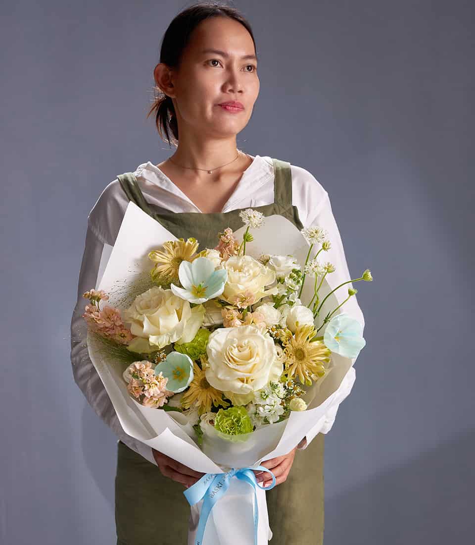 Ivory roses, blue anemones and champagne blooms bouquet with white wrapping and light blue ribbon