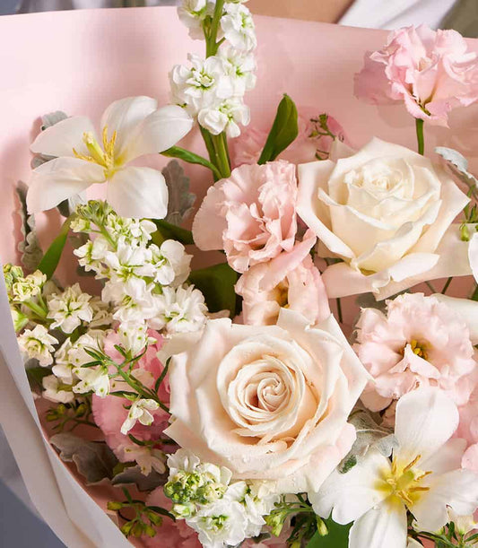Ivory and blush roses with white freesia pastel bouquet, wrapped in light pink paper with white ribbon