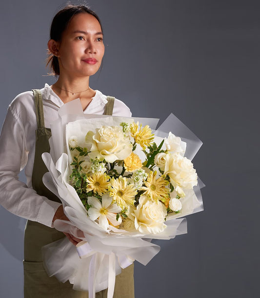 Elegant ivory rose and cream gerbera bouquet with yellow chrysanthemums, wrapped in white paper with silk ribbon bow
