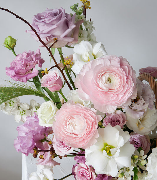 Lavender Grace flower basket with pink ranunculus, roses, and white lisianthus in soft pastels