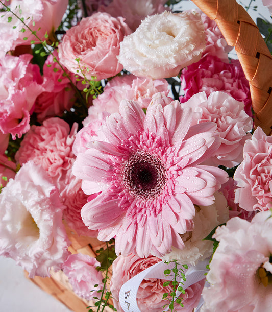 Pink and white fresh flower arrangement in woven basket with gerberas, roses and lisianthus for birthday gifting