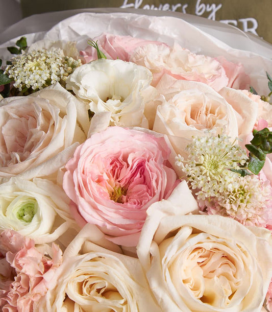 Elegant mixed bouquet of cream, pink and white roses with lisianthus and filler flowers in premium wrapping