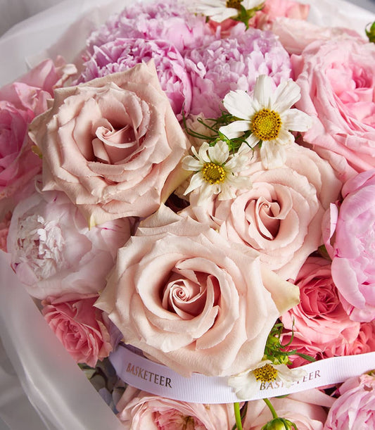 Blush peony and rose bouquet with cream roses and white daisies, wrapped in cellophane with white ribbon
