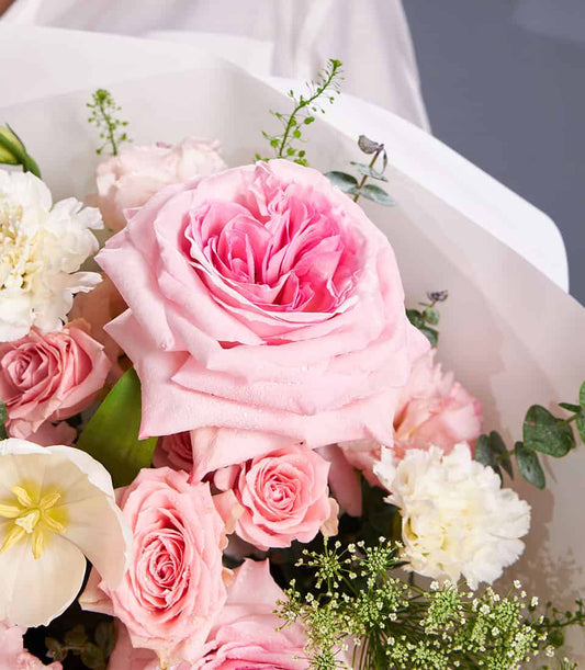 Blush pink roses and white tulips bouquet with eucalyptus greenery, wrapped in white paper