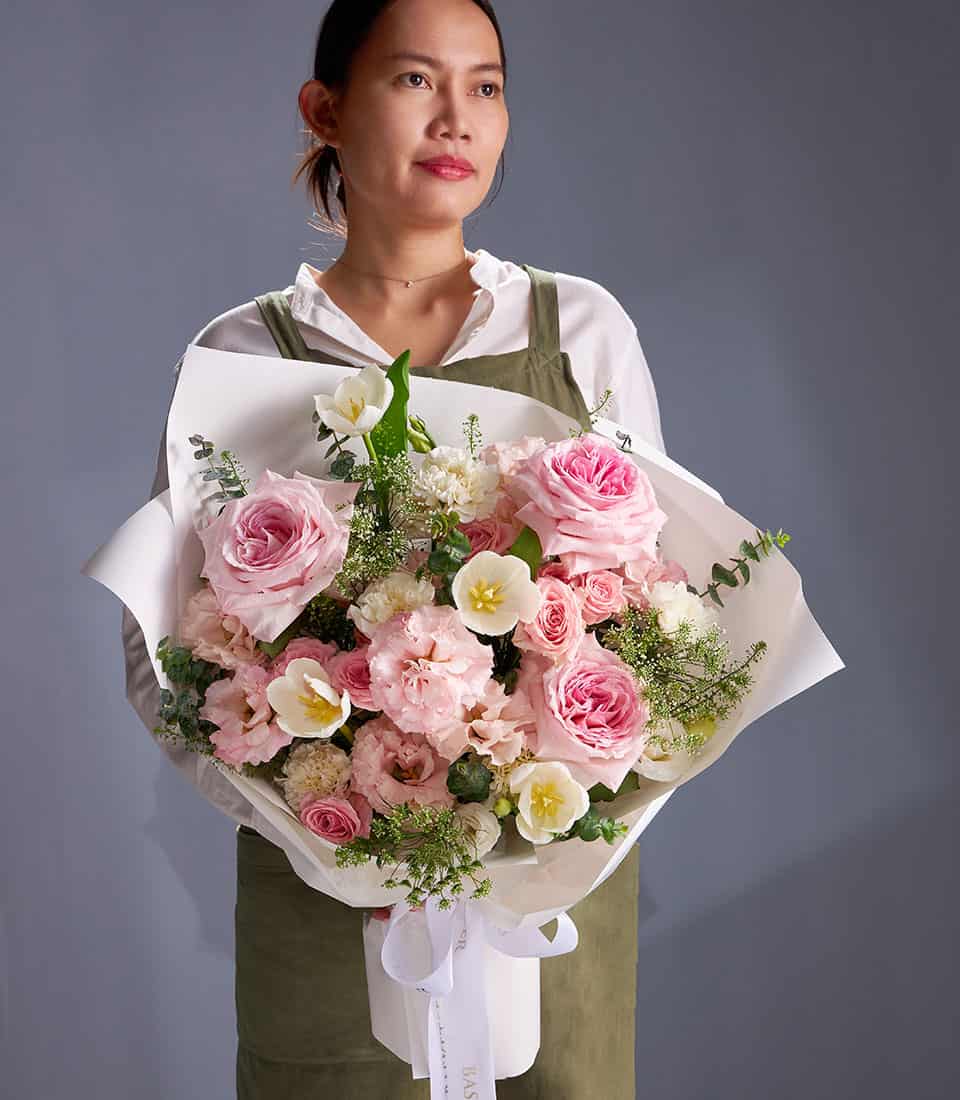 Blush pink roses and white tulips bouquet with carnations, wrapped in white paper and ribbon