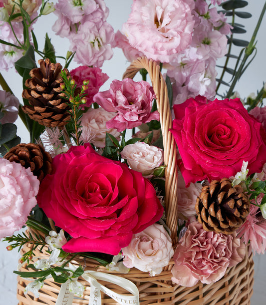 Crimson Charm flower basket with fuchsia and pink roses, pinecones, and cream ribbon for birthday gifts