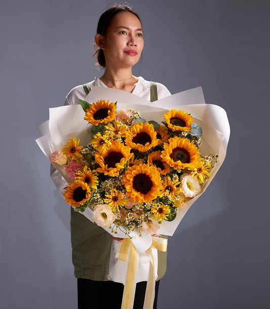 Vibrant sunflower and daisy garden bouquet with white wrapping and yellow ribbon