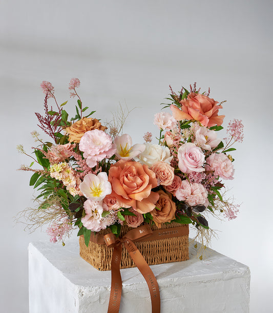 Toffee rose and pink lisianthus arrangement in woven basket with satin ribbon