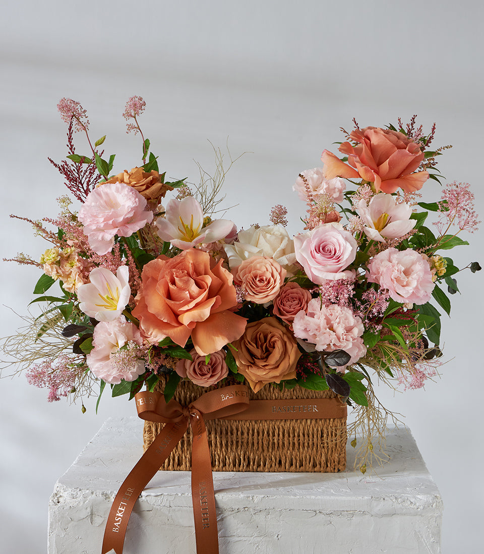 Caramel pink roses and lisianthus arrangement in woven basket with satin bow