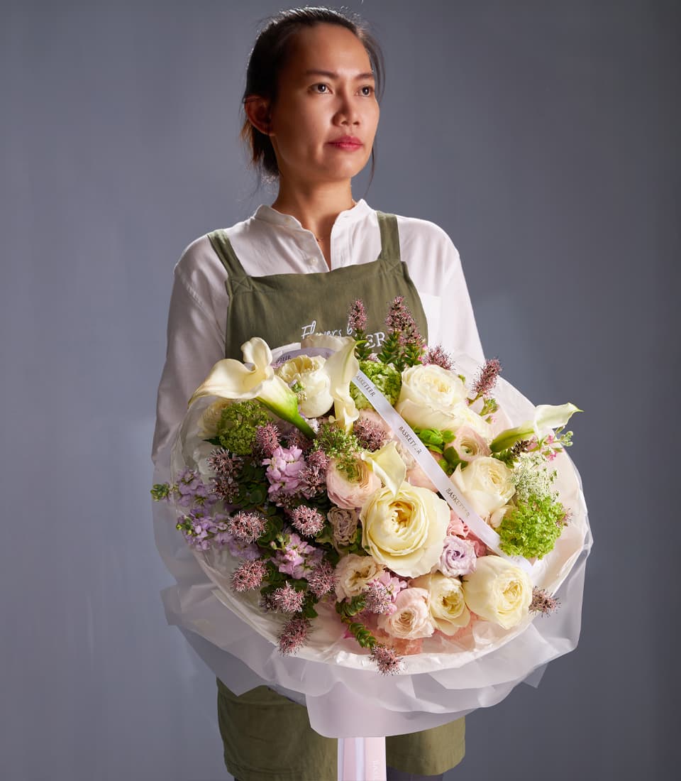 Elegant ivory rose and calla lily bouquet with pink garden roses and purple filler, wrapped in white tissue
