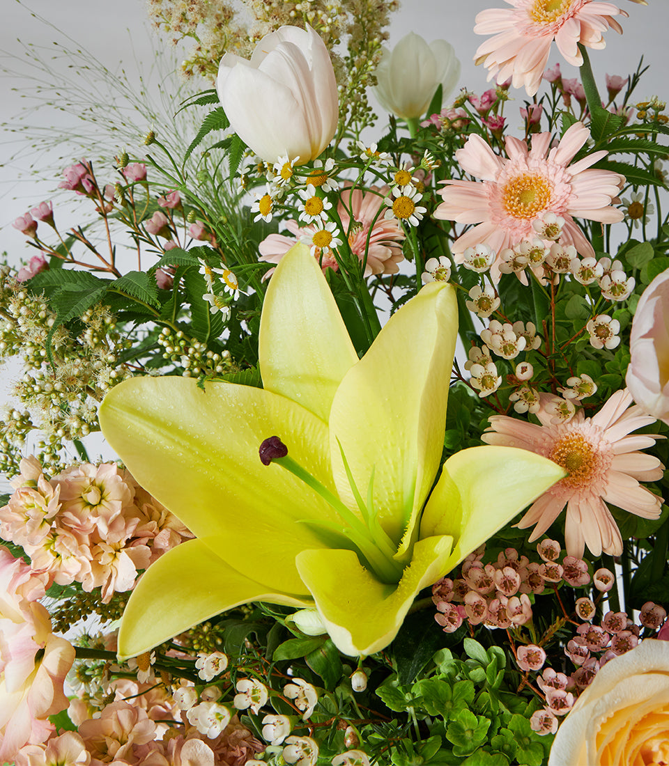 Yellow lilies and pink roses in pastel flower basket arrangement