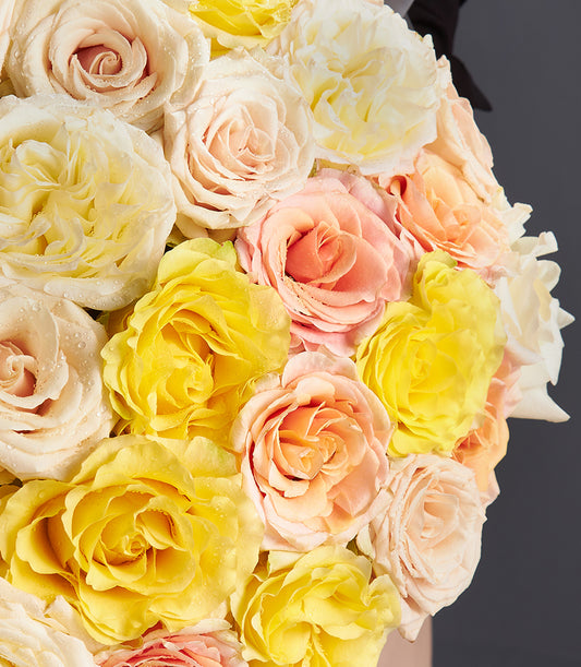 Vibrant yellow, peach, and cream fresh rose bouquet with dark ribbon accent