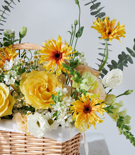 Vibrant yellow and white flower basket with roses, gerberas, and ranunculus for birthday celebrations