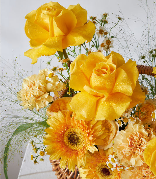 Yellow and orange roses with gerberas in woven basket, birthday flower gift