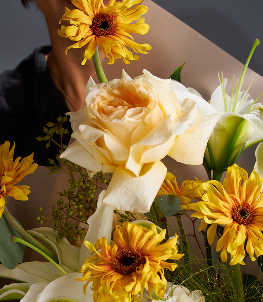 Yellow gerbera daisies and cream roses with white lilies in fresh luxury bouquet