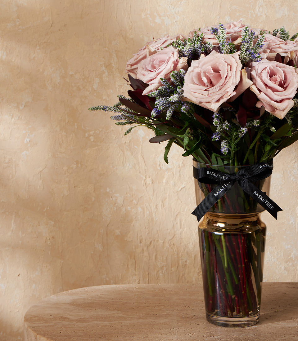 Light pink roses with burgundy foliage in two-tier glass vase, premium flower arrangement for gifting