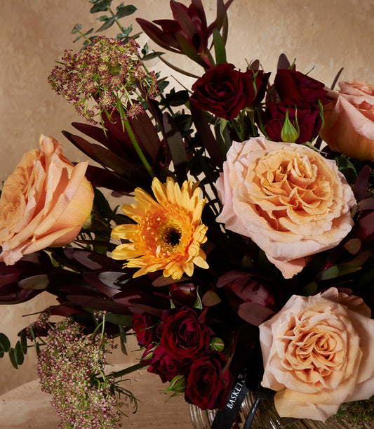 Peach, pink and red garden roses with yellow gerbera in tall glass vase, luxury gift arrangement