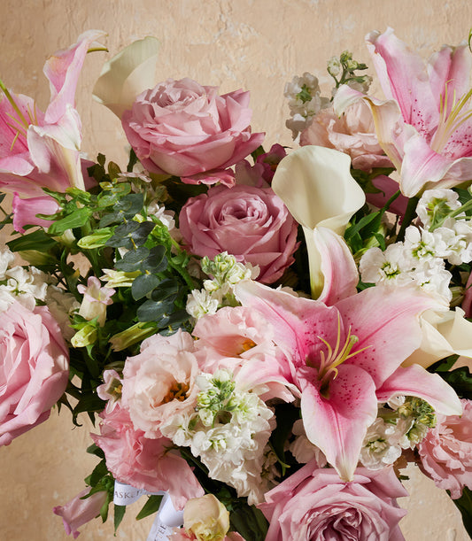 Pink and white fresh flower arrangement with lilies, roses, and calla lilies in elegant vase